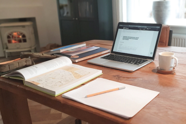 Home office with a notepad and laptop on a wooden desk